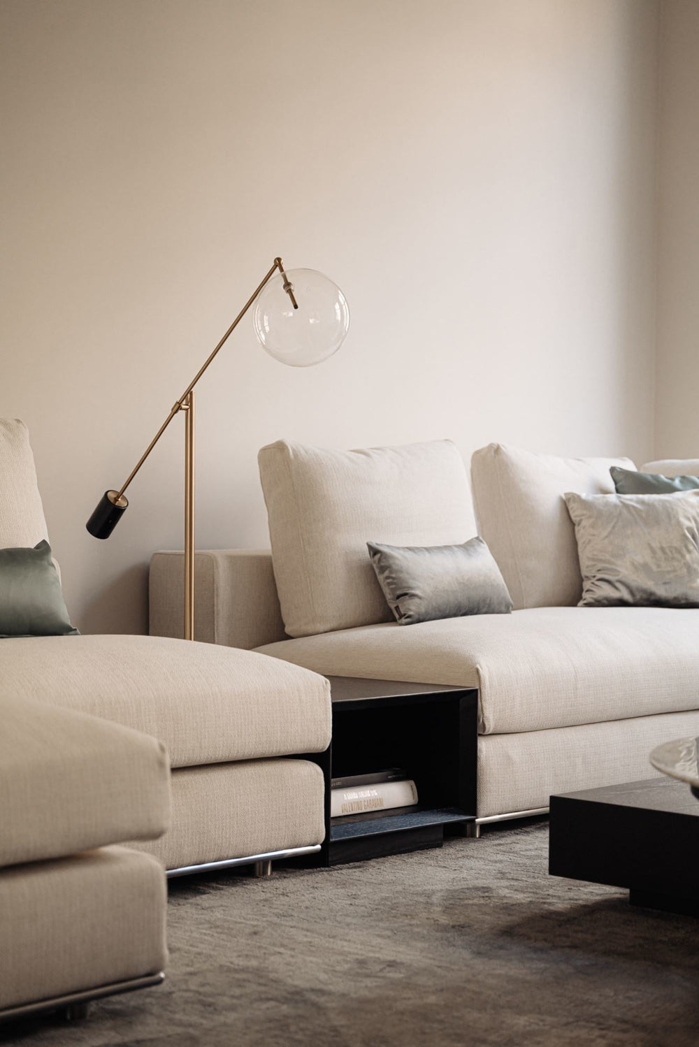 Bijzettafel Massimo in eiken Charcoal tussen lichte zitdelen in een woonkamer met vloerlamp.