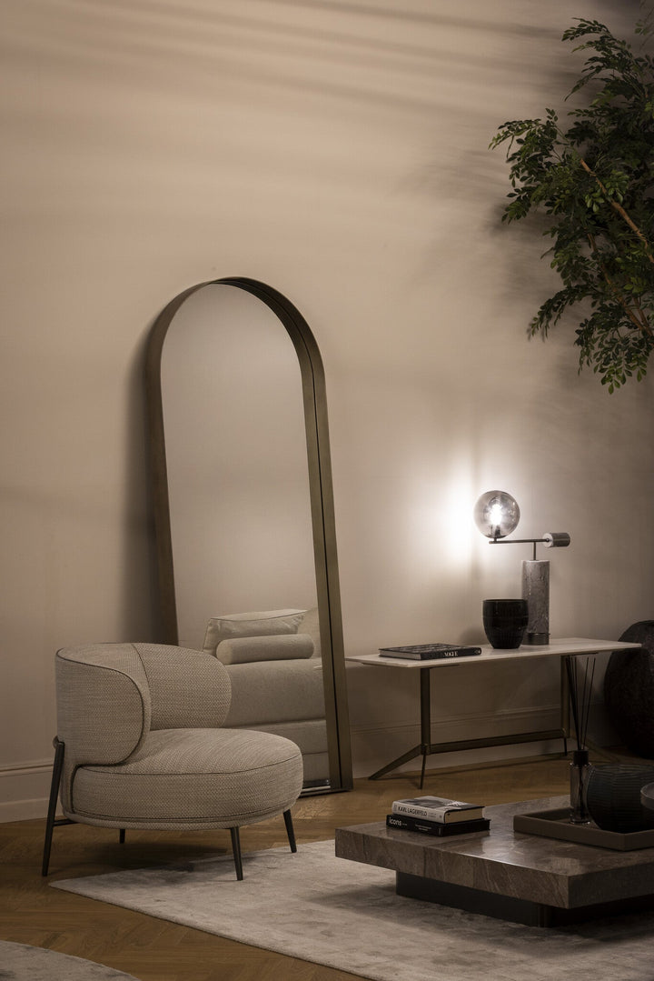 Fauteuil Ricardo in taupe met contrasterende bies bij een hoge spiegel en console.