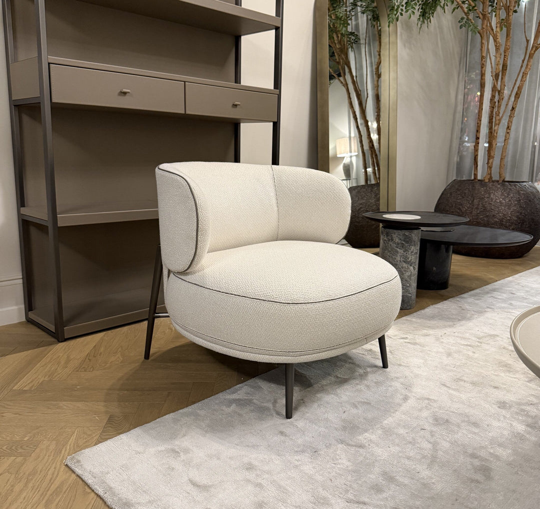 Fauteuil Ricardo in witbeige met contrasterende bies en slanke metalen poten in een zithoek met vloerkleed en bijzettafels.