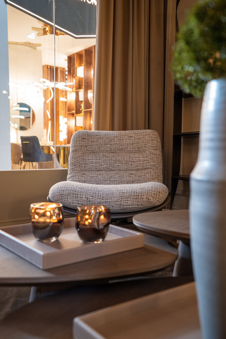 Fauteuil Alfonso in taupe bekleding in een warme zithoek met salontafels en kaarsen.