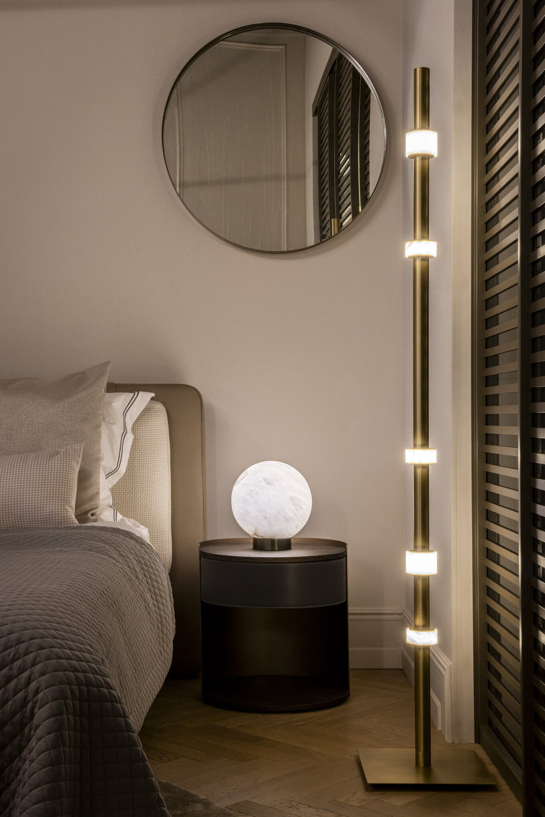 Nachtkastje Romeo met bronsafwerking en open opbergvak naast een bed met sfeerverlichting.