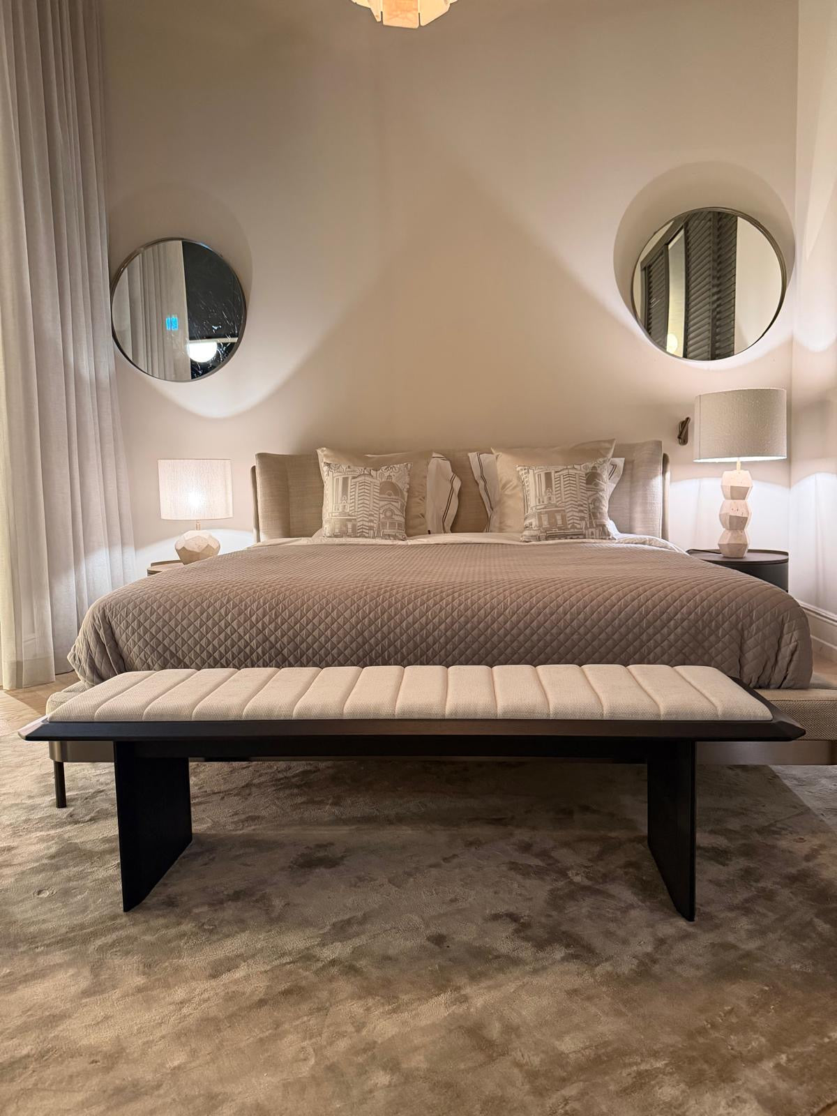 Bankje Serra in Charcoal met een licht gestoffeerde zitting aan het voeteneinde van een bed in een warme slaapkamer.